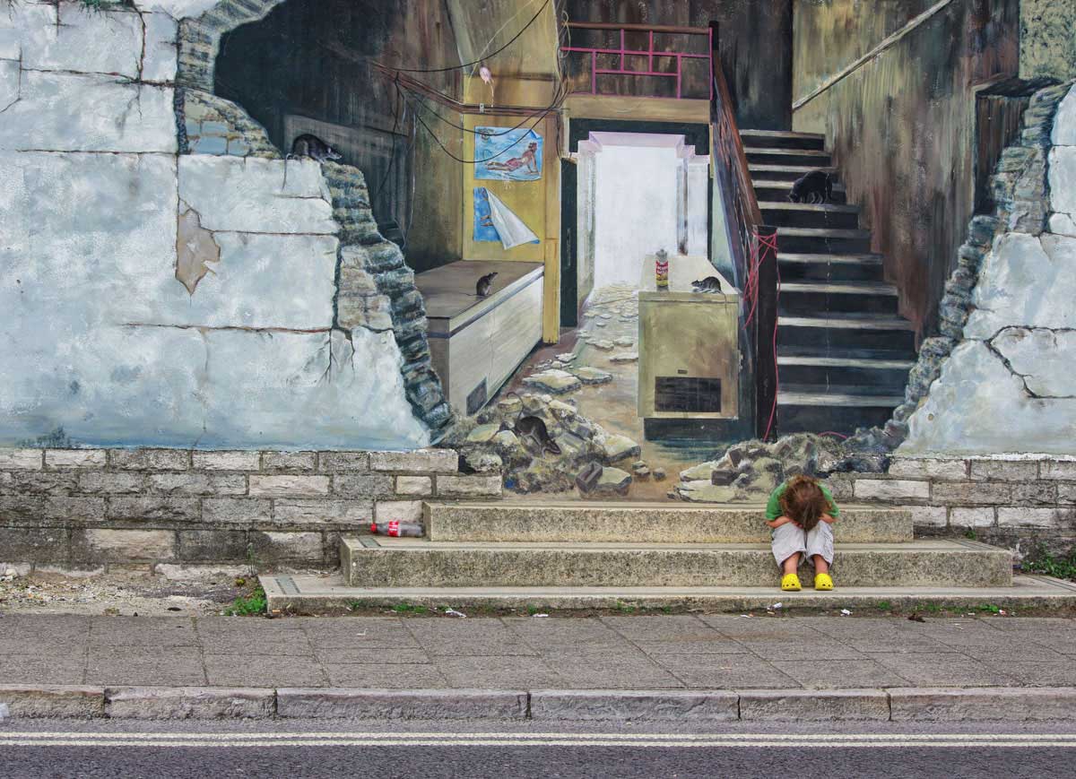 Child in a temper on the steps next to graffiti